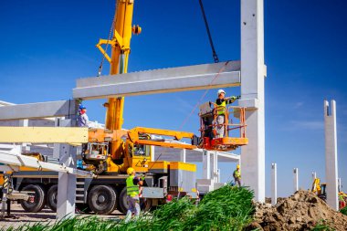 İşçiler vinçin yerden kalkmasına yardım ediyor, denge ve korku içinde.