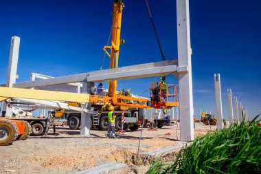 İşçiler vinçin yerden kalkmasına yardım ediyor, denge ve korku içinde.