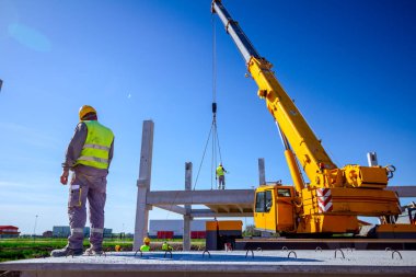 Patron büyük montaj için beton kirişini denetliyor, kontrol ediyor.