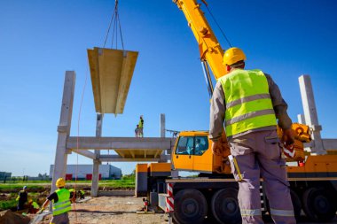 Patron büyük montaj için beton kirişini denetliyor, kontrol ediyor.