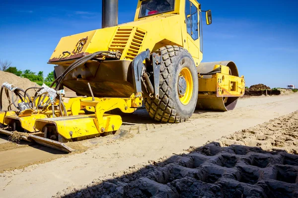 Plate compactor is mounted on road roller to compact soil at con