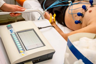 Elektrokardiyogram ekipmanı ile kardiyolog makineye vakum sensörleri ile bağlı olan hastanın kardiyogram testi yapıyor. 