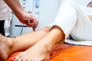 Fizyoterapist mıknatıs tedavisi ile hasta diz tedavi ediyor.