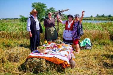 Muzlja, Vojvodina, Serbia, - July 06, 2019; Senior people rejoice and dance at harvest time, preparing for breakfast in retro style.