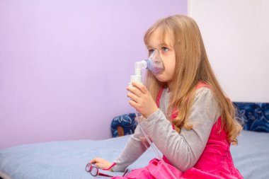 Astım sorunu olan bir çocuk yüzünde maskeyle solunum yapar..