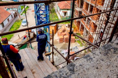 Katıcılar inşaat alanının üstündeki iskelenin tepesindeki ahşap platformda duruyorlar..