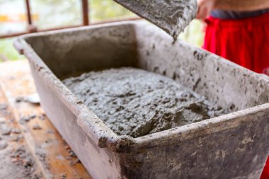 İşçi kürekle harç dolduruyor, havan sığ plastik konteynır..