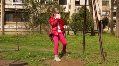 Tıbbi maskeli ve eldivenli küçük kız COVID 19 virüsünden korunmak için tek başına sallanıyor, Corona. Canon EOS R 4K All-I