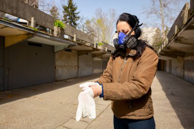 Yüzünde filtre maskesi olan kadın COVID-19 virüsüne karşı korunmak için ellerine lastik eldiven takıyor.. 