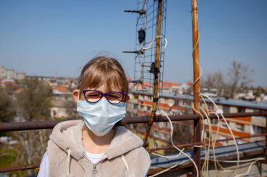 Küçük kız COVID-19 virüsünden korunan tıbbi bir maske takıyor, Corona.. 