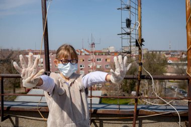Medya baskısını durdurun. Tıbbi maske takan ve eldiven takan küçük kız ellerini, jestlerini, sosyal mesafelerini, uzak durduğunu, COVID-19 virüsüne karşı korunduğunu gösteriyor..