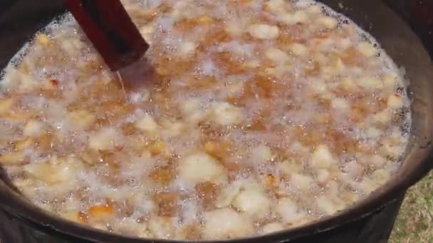传统的方法融化新鲜猪肉脂肪 使裂纹在深铁锅 用长木勺搅拌桩 — 图库视频影像