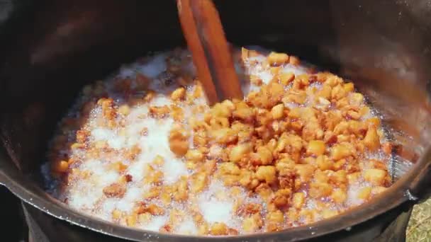 新鮮な豚肉の脂肪 ベーコンを溶かす伝統的な方法は 深い鉄の釜でパチパチ作る 長い木製のスプーンとの混合杭 — ストック動画