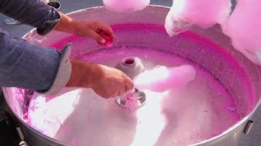 Özel bir şeker makinesinde dönen tahta çubukla pembe pamuk yapma süreci.