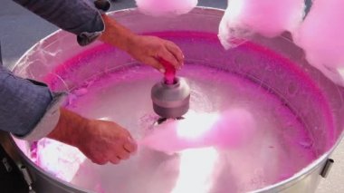 Özel bir şeker makinesinde dönen tahta çubukla pembe pamuk yapma süreci.