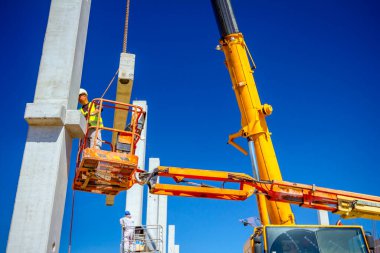 Vinçler-Mobil vinç işletim ve derleme beton kiriş yüksek yerde çalışıyor. Yükseklik işçi iskelet bina truss çiziyor.