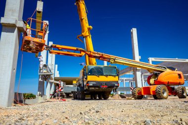 Vinçler-Mobil vinç işletim ve derleme beton kiriş yüksek yerde çalışıyor. Yükseklik işçi iskelet bina truss çiziyor.