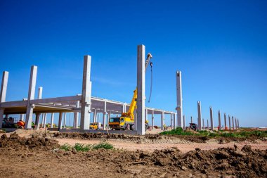 Montaj makine ile endüstriyel bina büyük bir beton iskelet, insanlar çalışıyoruz. Şantiyede görüntüle.