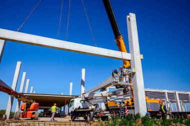 Vinçler-Mobil vinç işletim ve derleme beton kiriş yüksek yerde çalışıyor. Yükseklik işçi iskelet bina truss çiziyor.