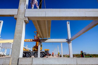 İşçi için derleme büyük inşaat beton kiriş yönetmek için Mobil vinç yardım ediyor.