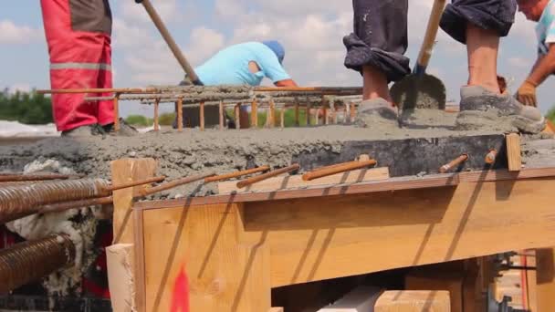 建筑工人们正在用铲子把木模中的新鲜混凝土与钢筋对齐 — 图库视频影像