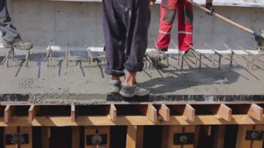 İnşaat işçileri, tahta kalıptaki taze betonu güçlendirmek için kürek kullanıyorlar..