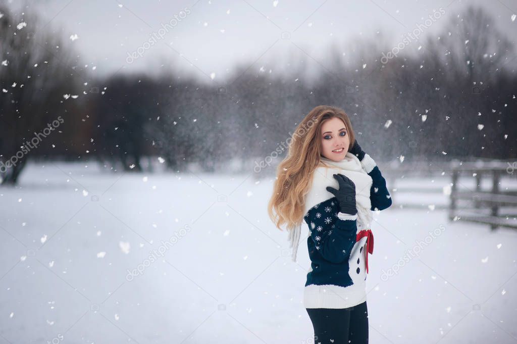 Portrait of a beautiful girl on a walk in the park in snowy winter