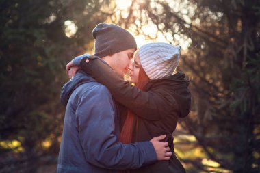 Genç bir çift, modern bir şehrin ortasında yürürken sarılır ve gülümser.