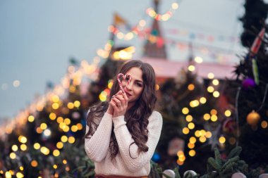 Yanan maytap ya da havai fişek tutan mutlu bir çocuğun Noel portresi, arka planda karlı bir kış ağacı. Şehirde yeni yıl tatili.