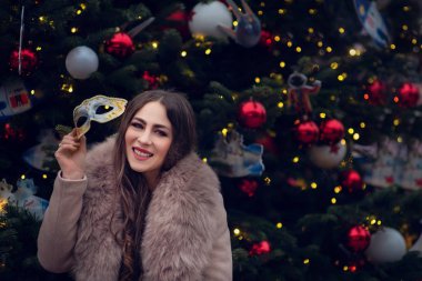 Noel 'de elinde yanan maytap ya da dışarıda havai fişek tutan mutlu bir kızın portresi arka planda karlı bir kış ağacı. Şehirde yeni yıl tatili.