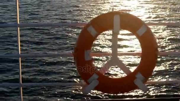 Rode reddingsboei op een boot oversteken van de zee bij zonsondergang — Stockvideo