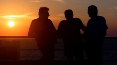 gün batımında denize arka plan üzerinde konuşmak üç tanımlanamayan kişi