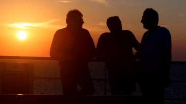 gün batımında denize arka plan üzerinde konuşmak üç tanımlanamayan kişi