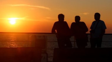 gün batımında denize arka plan üzerinde konuşmak üç tanımlanamayan kişi
