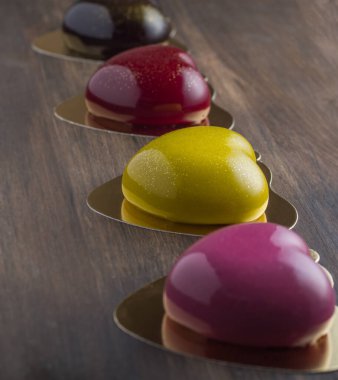 multi-colored heart-shaped mousse cakes on wooden background