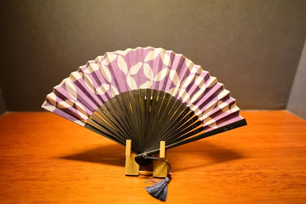 Purple Japanese folding fan on the wooden table.