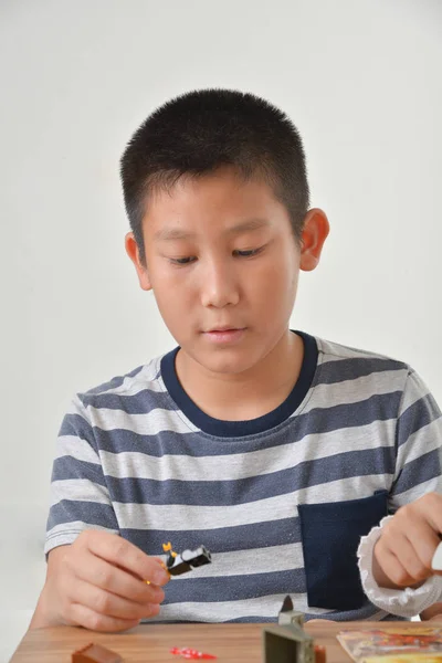 Asiatisk pojke leker med lego. isolerad på en grå bakgrund — Stockfoto
