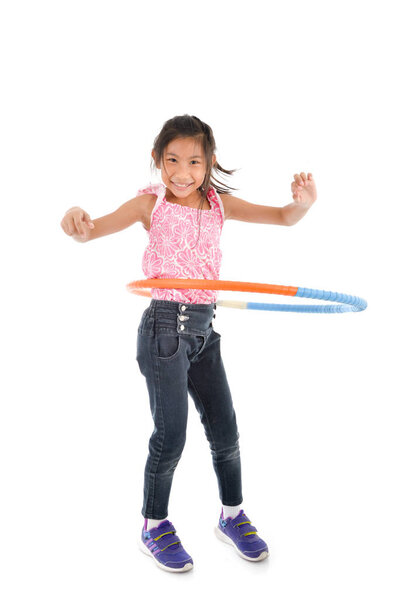 Portrait of happy little Asian child girl playing hulahoop on is