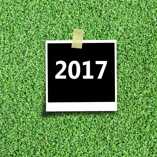 Ramka na zdjęcia na zielonej trawie z wiadomości szczęśliwego nowego roku. — Zdjęcie stockowe