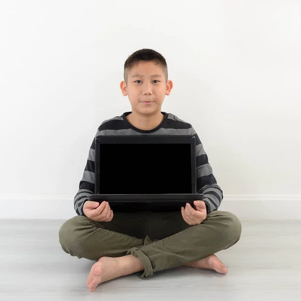 Asiático menino mostrando laptop em branco em casa . — Fotografia de Stock