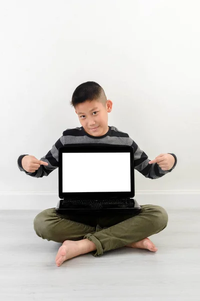 Asiático menino mostrando laptop em branco em casa . — Fotografia de Stock