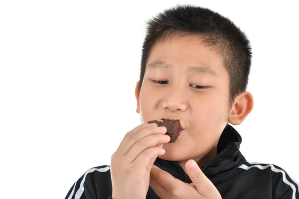 Portrét asijské chlapce jíst brownie dort na bílém. — Stock fotografie
