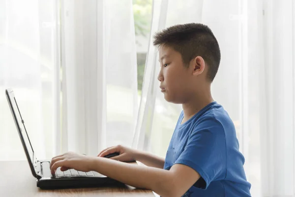 Jovem menino asiático usando a tecnologia laptop em casa . — Fotografia de Stock