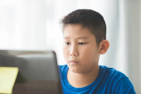 Unga asiatiska pojke med laptop teknik hemma. — Stockfoto