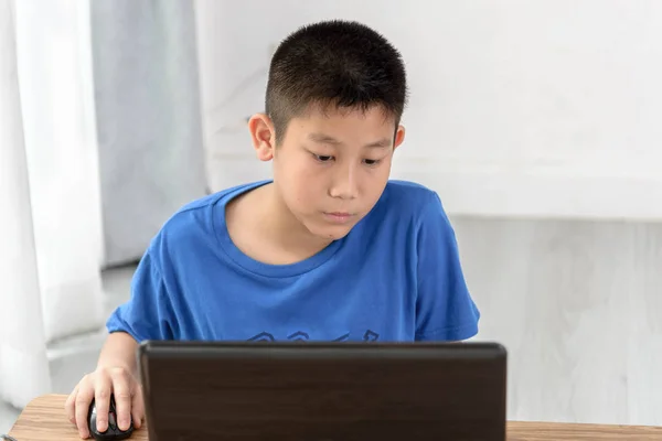 Jeune garçon asiatique utilisant la technologie de l'ordinateur portable à la maison . — Photo