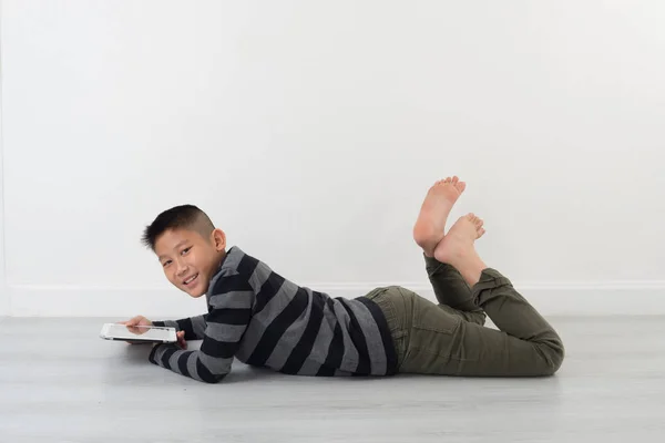 Boy lying on floor  and holding pad at home — Stock Photo, Image
