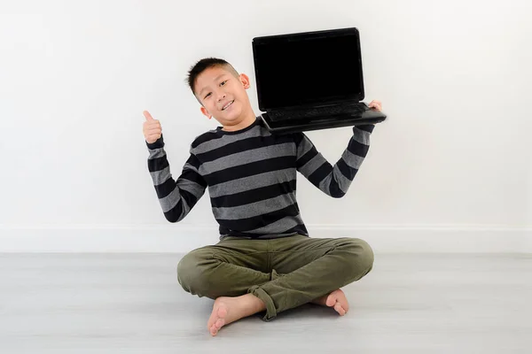 Asiático menino mostrando laptop em branco em casa . — Fotografia de Stock