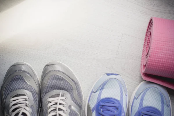 Брудне спортивне взуття на підлозі з йога килимом вдома. Стиль життя con — стокове фото