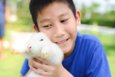 Asyalı çocuk gülümseme ve tavşan açık, seçici odak ile oynamak