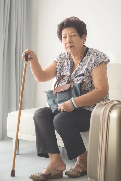 Asijské starší žena sedí doma a připravena k cestování — Stock fotografie